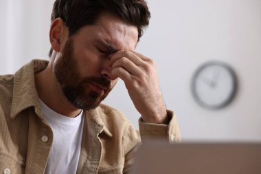Ofiste baş ağrısı çeken yorgun bir adam.