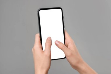 Akıllı telefondan gri arkaplana mesaj yazan kadın, yakın plan