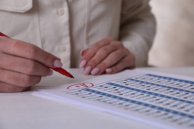 Okul derecesi. Öğretmen A harfini beyaz masadaki cevap kağıdına artı işareti ile yazıyor. Yakın plan.