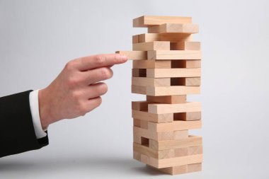 Açık gri arka planda Jenga oynayan kadın, yakın plan
