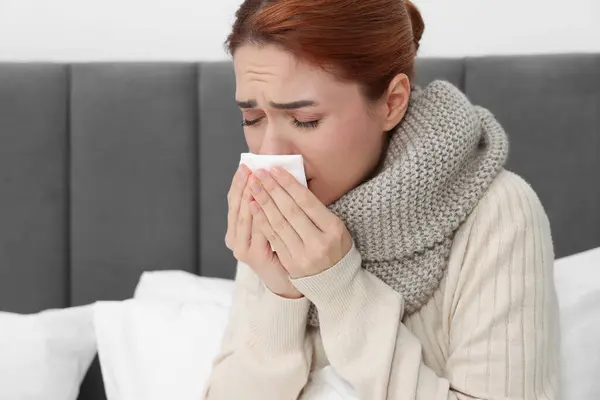 Woman with tissue coughing on bed, space for text. Cold symptoms