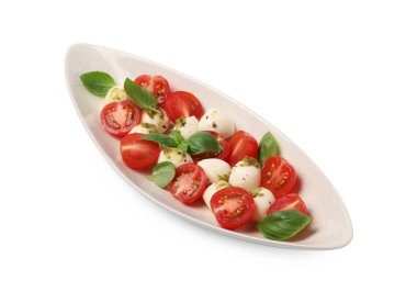 Bir tabak lezzetli Caprese salatası, mozzarella, domates, fesleğen ve pesto sosu beyaz üzerine izole edilmiş.