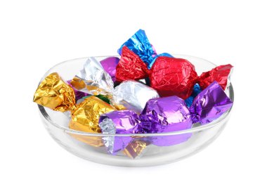 Beyaza izole edilmiş renkli ambalajlarla bir sürü lezzetli şekerle dolu bir kase.
