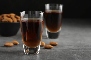 Lezzetli amaretto likörlü bardaklar ve gri masada badem, yakın plan. Metin için boşluk