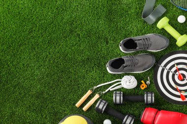 Farklı spor aletleri ve yeşil çimlerin üzerinde spor ayakkabıları, düz yatış. Metin için boşluk