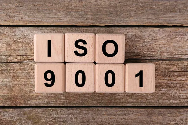 International Organization for Standardization. Cubes with abbreviation ISO 9001 on wooden table, top view