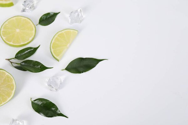 Состав со свежими лаймами, листьями и кубиками льда на белом фоне. Пространство для текста