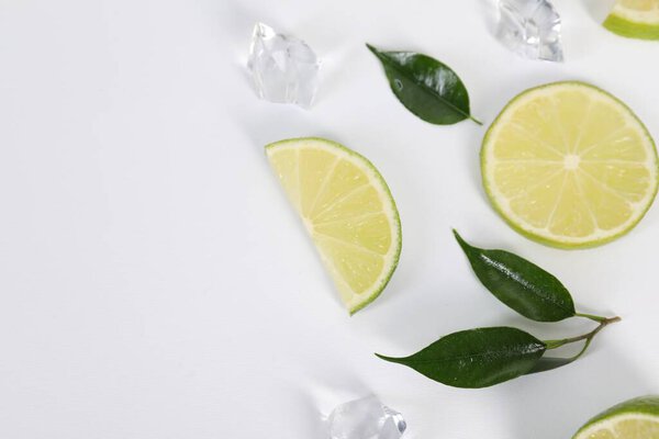 Состав со свежими лаймами, листьями и кубиками льда на белом фоне. Пространство для текста