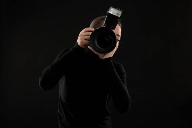 Profesyonel fotoğrafçı siyah arkaplanda fotoğraf çekiyor.