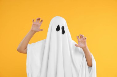 Sarı arka planda beyaz hayalet kostümlü kadın. Cadılar Bayramı