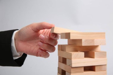 Açık gri arka planda Jenga oynayan kadın, yakın plan