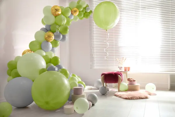 Balloon garland near white wall in room. Festive decor