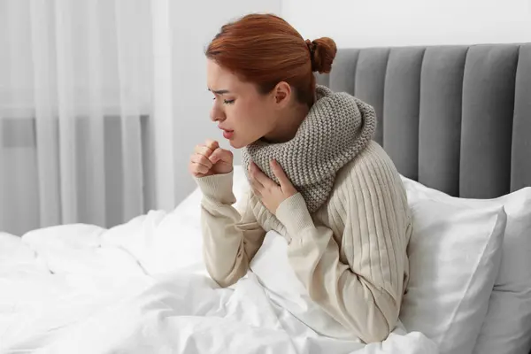 Woman with scarf coughing at home, space for text. Cold symptoms