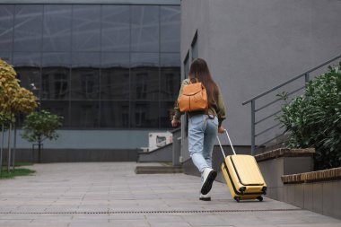 Geç kalmak. Sırt çantası ve bavulu olan bir kadın dışarıda yürüyor, mesaj için arka planı olan bir kadın.