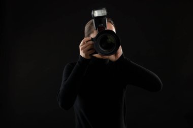 Profesyonel fotoğrafçı siyah arkaplanda fotoğraf çekiyor.