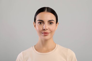 Gri arka planda güzel bir genç kadının portresi