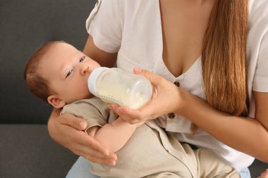 Anne, şirin çocuğunu bebek mamasıyla evde besliyor.