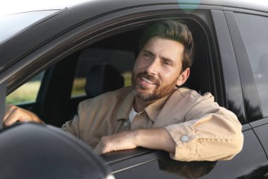 İyi yolculuklar. Arabasını kullanan mutlu sakallı adam, dışarıdan manzaralı.