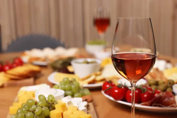 Glass of rose wine and appetizers served on wooden table, selective focus. Space for text