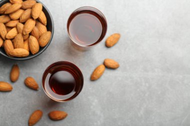 Lezzetli amaretto likörlü bardaklar ve gri masada bademler, düz konum. Metin için boşluk