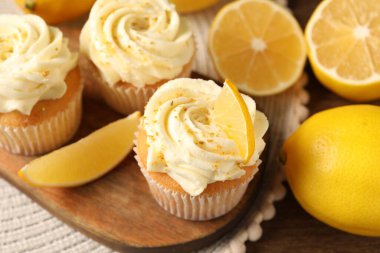 Kremalı, lezzetli ve limonlu kapkekler ahşap masada, yakın plan.