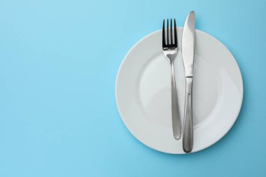 Temiz tabak, çatal ve bıçak açık mavi arka plan, üst manzara. Metin için boşluk