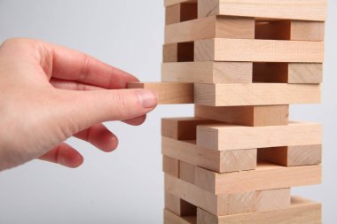 Açık gri arka planda Jenga oynayan kadın, yakın plan