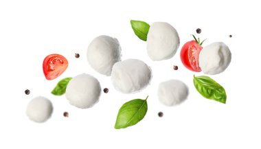 Mozzarella topları, domatesler, fesleğen yaprakları ve beyaz arka plana düşen biberler.