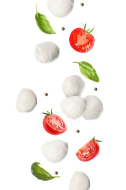 Mozzarella topları, domatesler, fesleğen yaprakları ve beyaz arka plana düşen biberler.