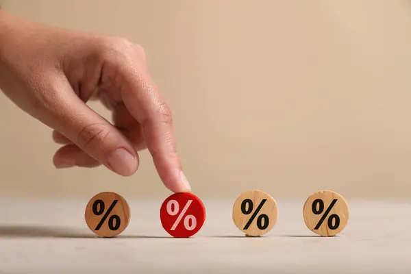 Best mortgage interest rate. Woman touching red wooden circle with percent sign on table, closeup