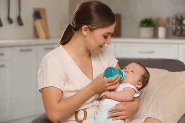 Anne, şirin çocuğunu bebek mamasıyla evde besliyor.