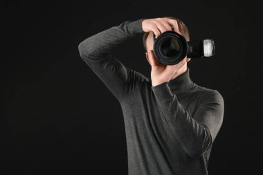 Profesyonel fotoğrafçı siyah arkaplanda fotoğraf çekiyor.