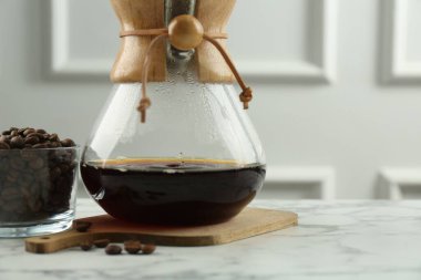 Cam kimya kahve makinesi, beyaz mermer masada kahve ve fasulye, yakın plan. Metin için boşluk