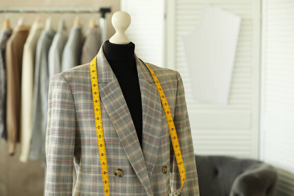 Манекен с курткой и измерительной лентой в швейной мастерской, место для текста
