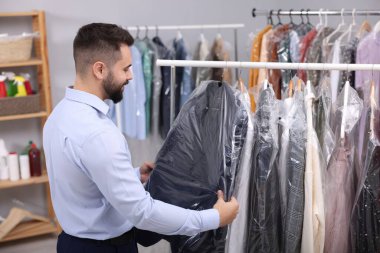 Kuru temizleme servisi. İşçi içeride askıdan ceket alıyor.