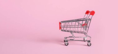 Pembe arka planda küçük metal alışveriş arabası, metin için boşluk