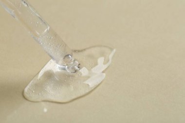 Bej arka planda kozmetik serumu olan bir boru, yakın plan. Metin için boşluk