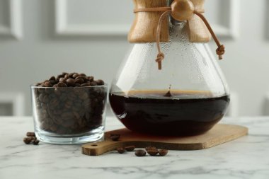 Cam kimya kahve makinesi, kahve ve fasulye kasesi beyaz mermer masada, yakın plan.