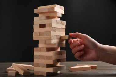 Masada koyu gri arka planda Jenga oynayan kadın, yakın plan