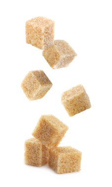 Beyaz arkaplana düşen kahverengi şeker küpleri