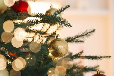 Işık arka planında neşeli toplarla süslenmiş Noel ağacı, yakın plan