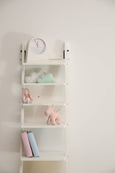 Shelving unit with toys near light wall in child room