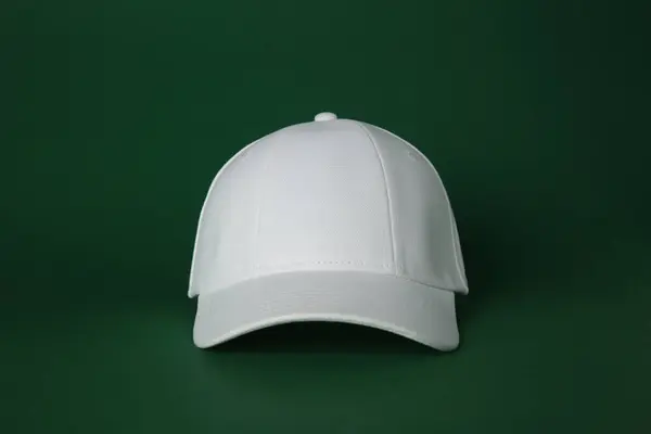 Stylish white baseball cap on dark green background