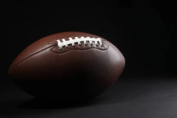 American football ball on black background. Space for text