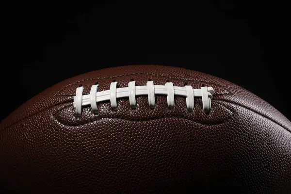 American football ball on black background, closeup