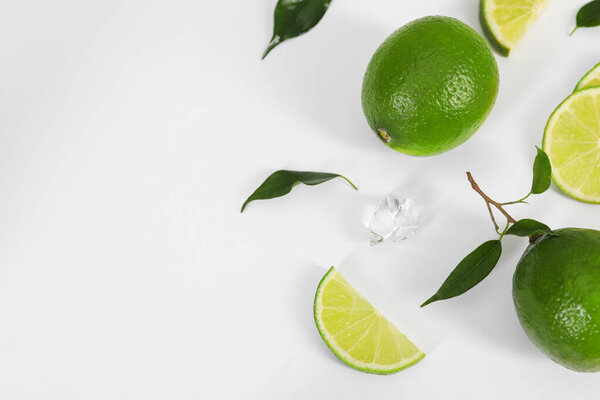 Плоская композиция со свежими лаймами, листьями и кубиками льда на белом фоне. Пространство для текста
