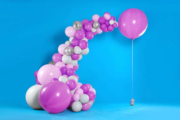 Balloon garland near light blue wall. Festive decor