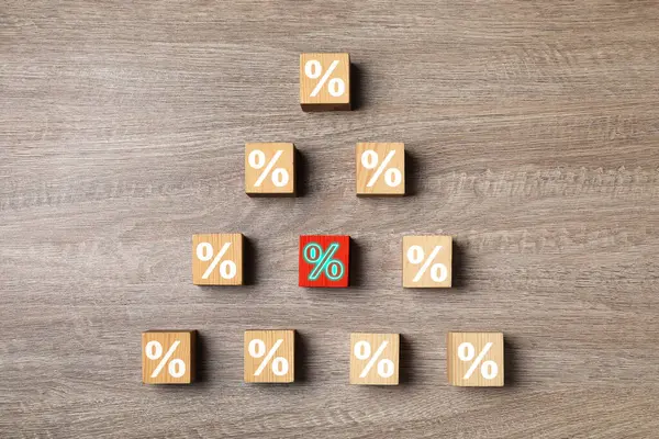 Best mortgage interest rate. Red cube with percent sign among others on wooden table, flat lay