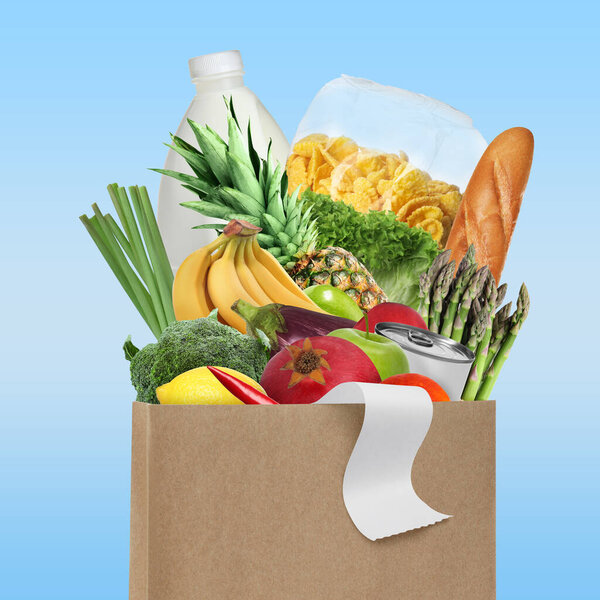 Paper bag with different products and receipt on light blue background