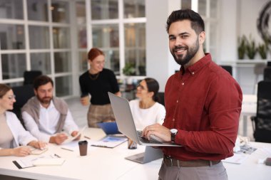 Ofiste birlikte çalışan bir ekip. İçerideki bilgisayarlı mutlu adam.